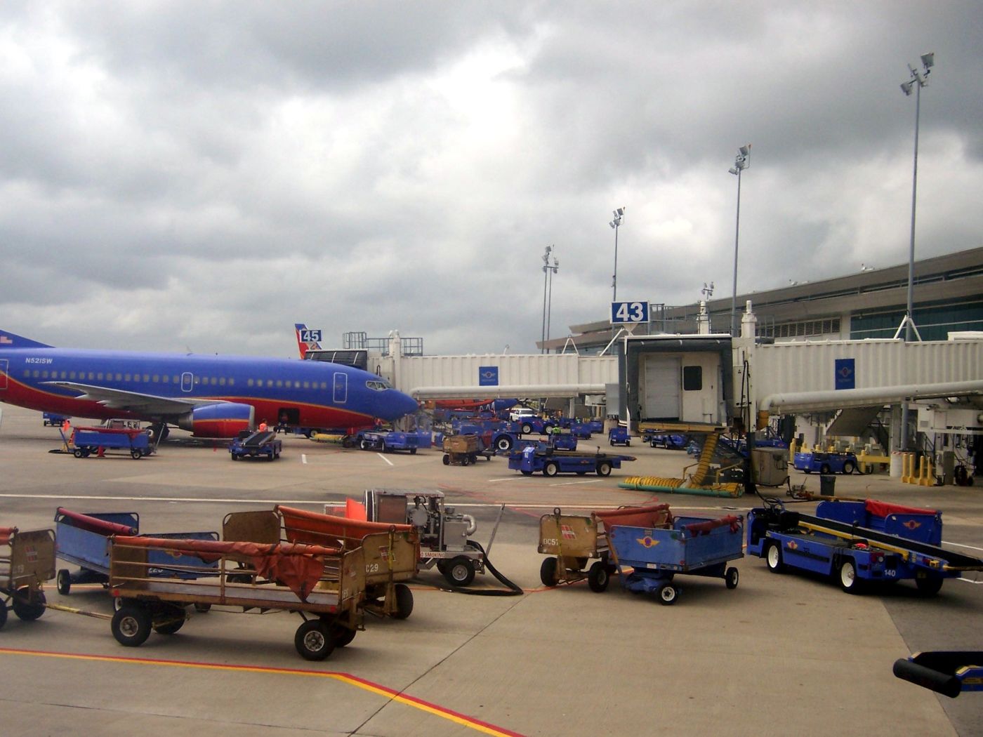 Baggage carts and belt loaders staged around a Southwest Airlines 737 at the gate